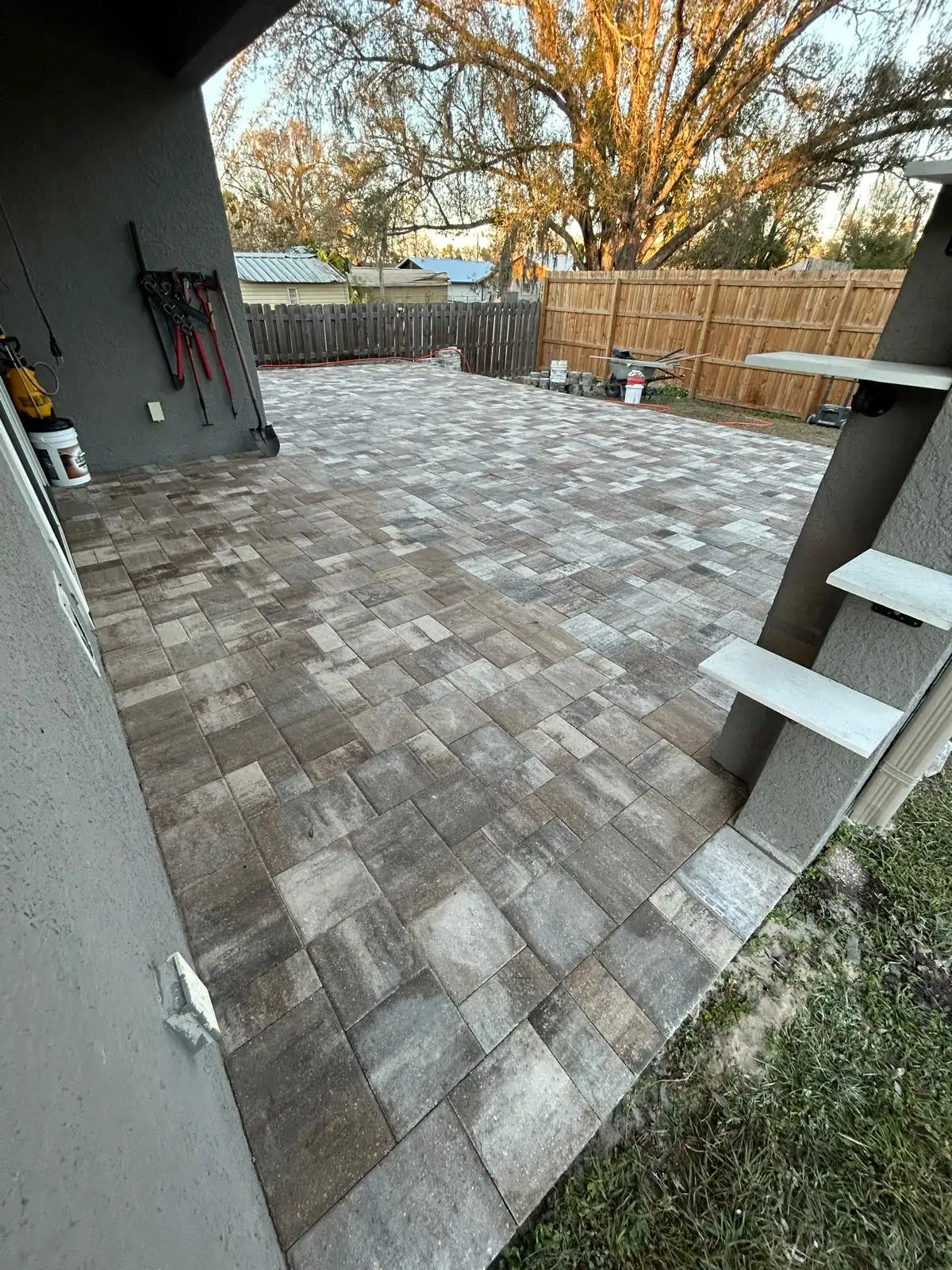 View from the covered lanai across the finished multi-tone concrete paver patio to the back fence.