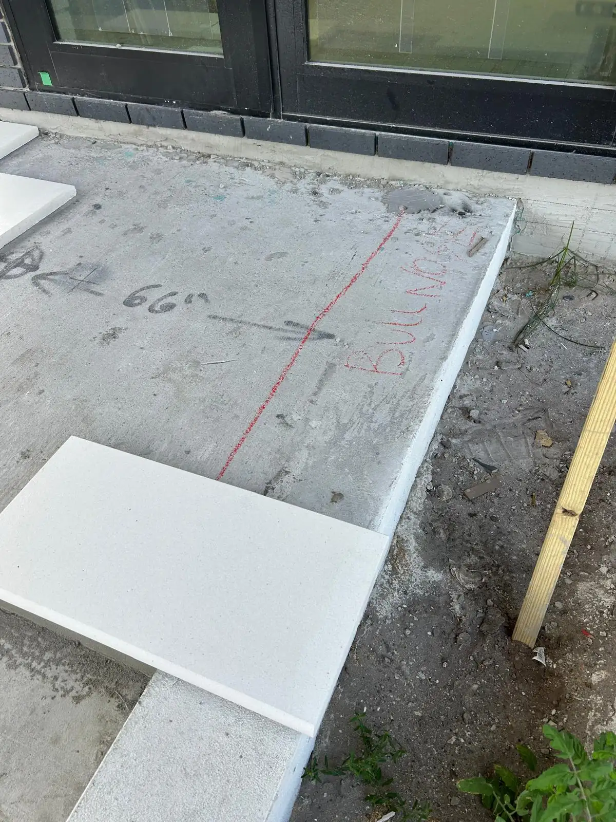 Red chalk bullnose line marked on a bare concrete landing with white stone treads set alongside