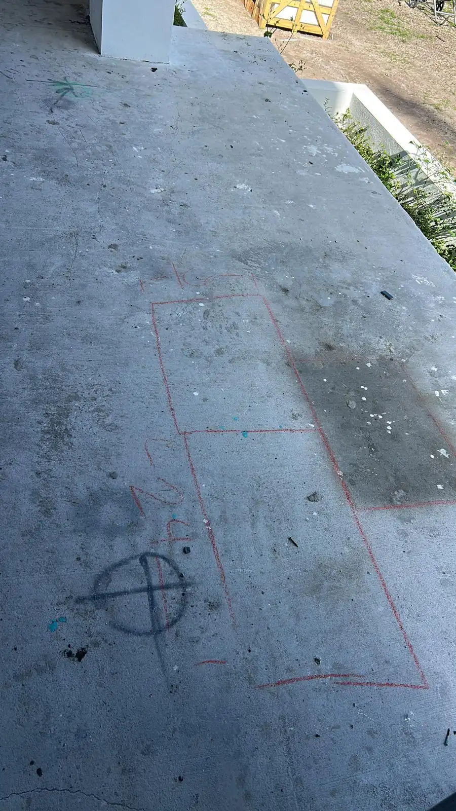 Chalk layout lines marked on a bare concrete landing slab before the white stone paving was set