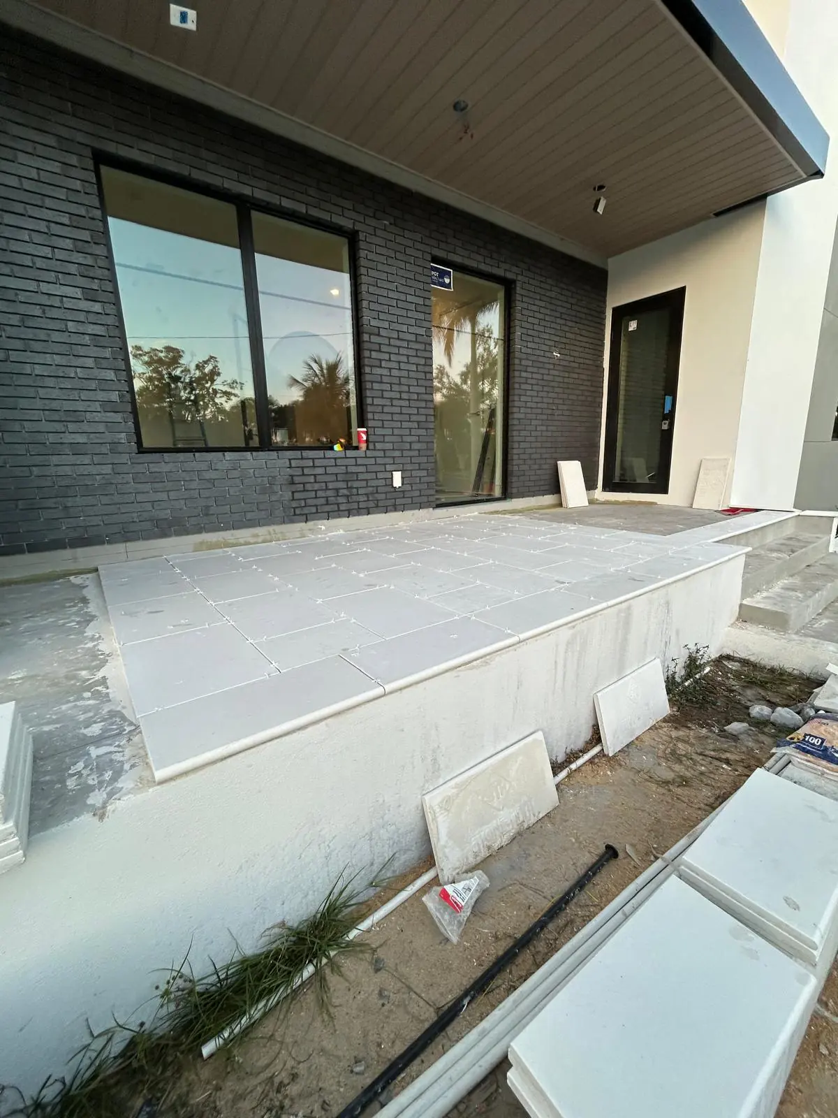 Raised front landing paved in large white stone with spacers still in place against dark brick