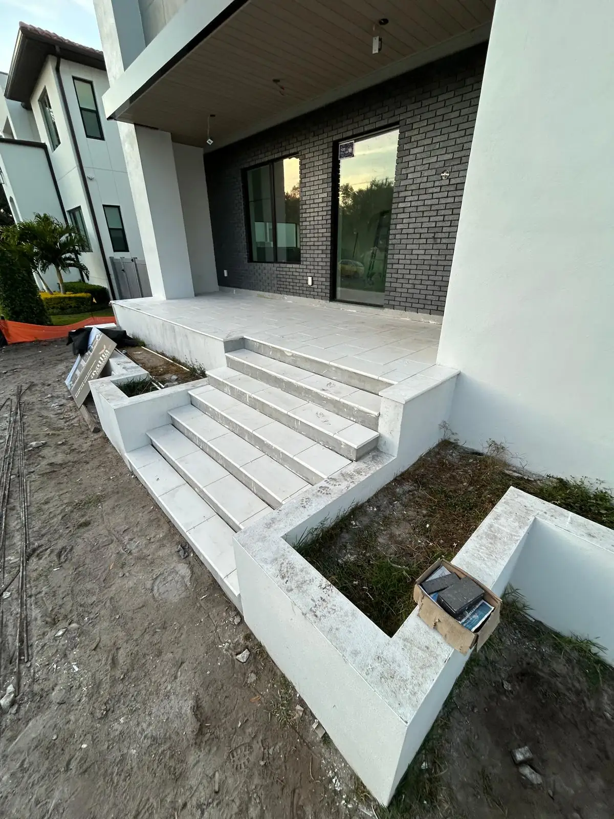 Finished white stone entry steps and landing with low white planter walls at a new build home