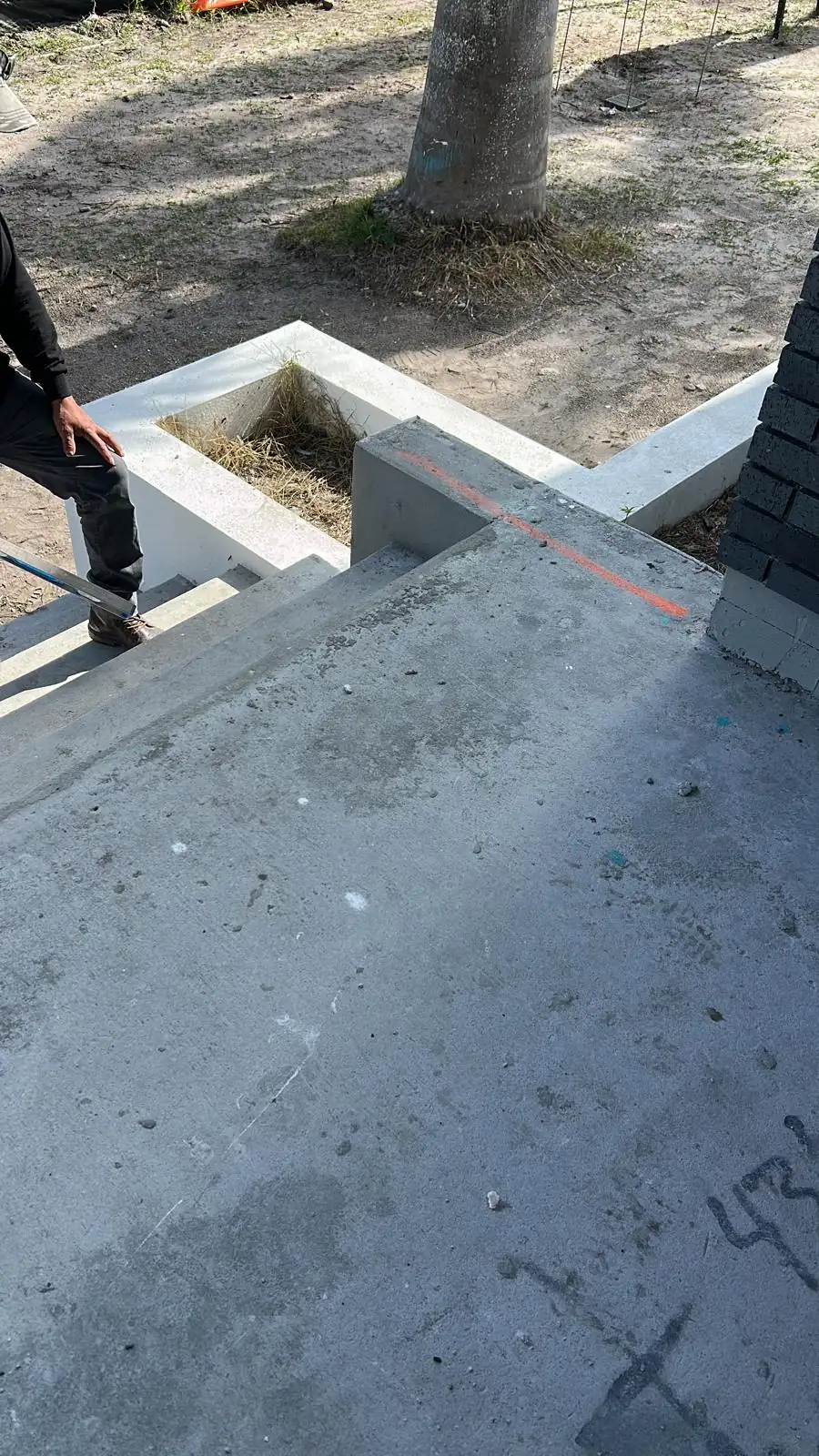 Bare concrete entry steps and landing marked out, with the white stucco planter box already formed