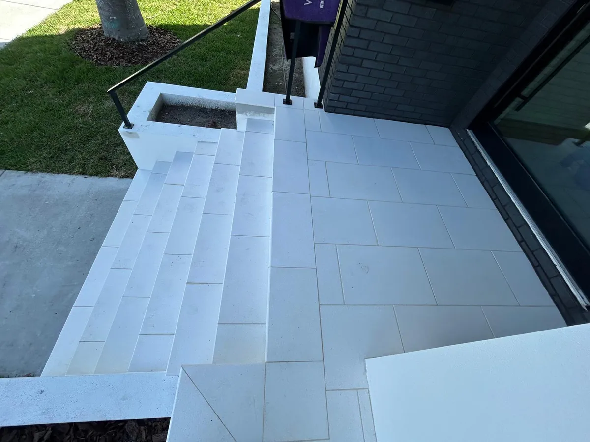 Overhead view of the front entry landing, stone step run and low white planter by the brick wall