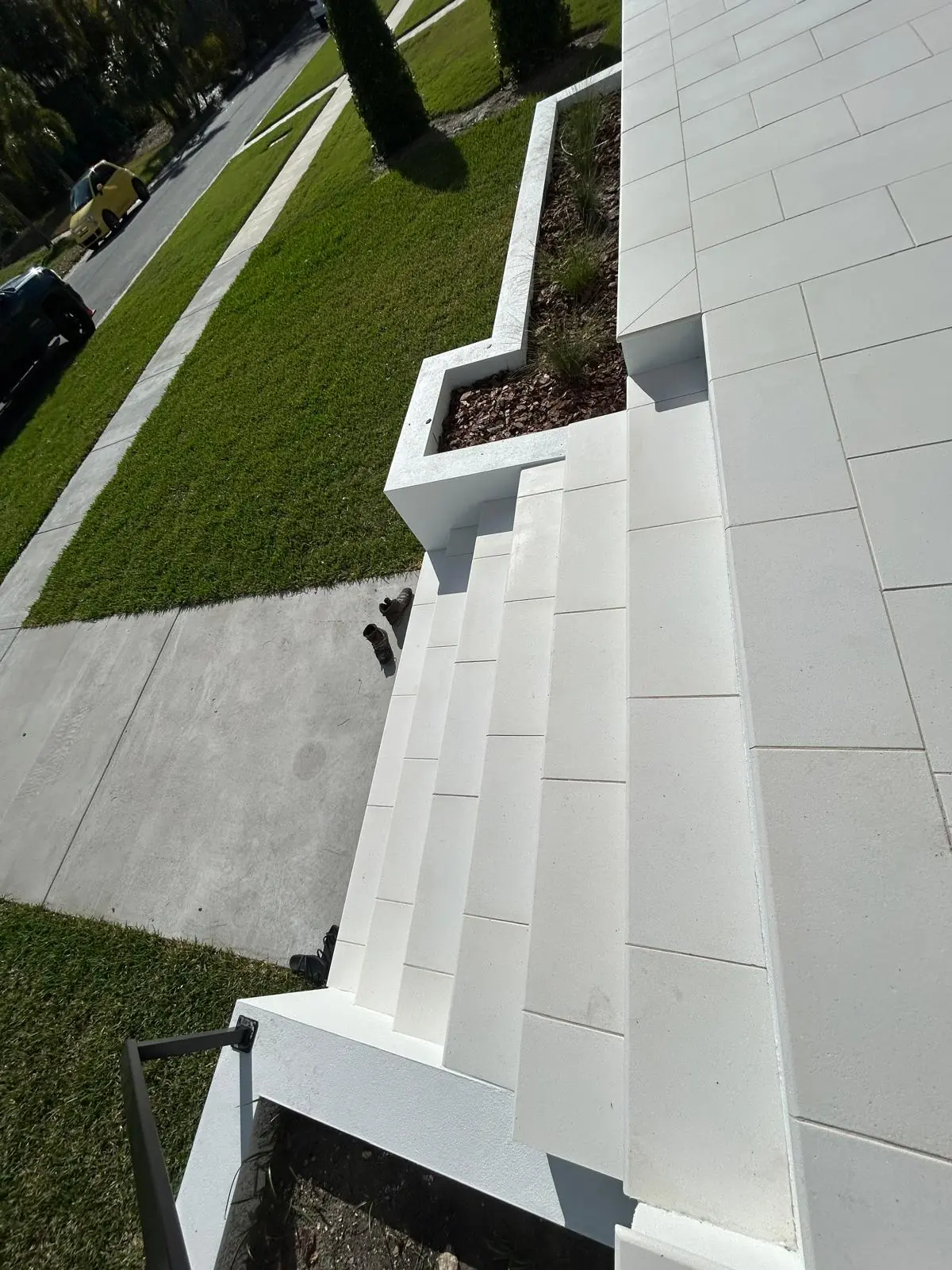 Stone front steps seen from above, with the stepped white planter wall running down to the sidewalk