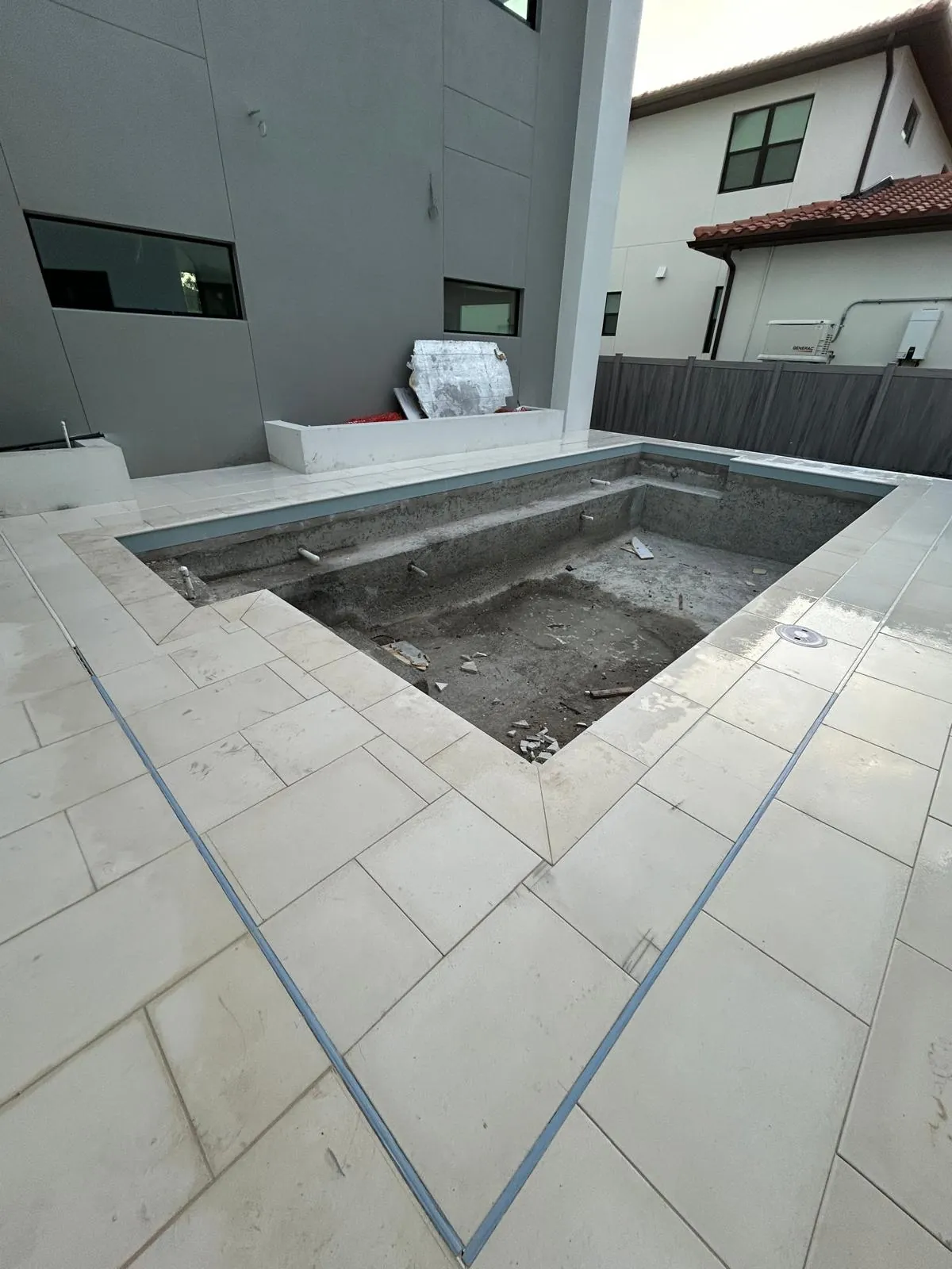 Mitred corner of the white stone pool deck with coping set along the edge of an unfilled pool