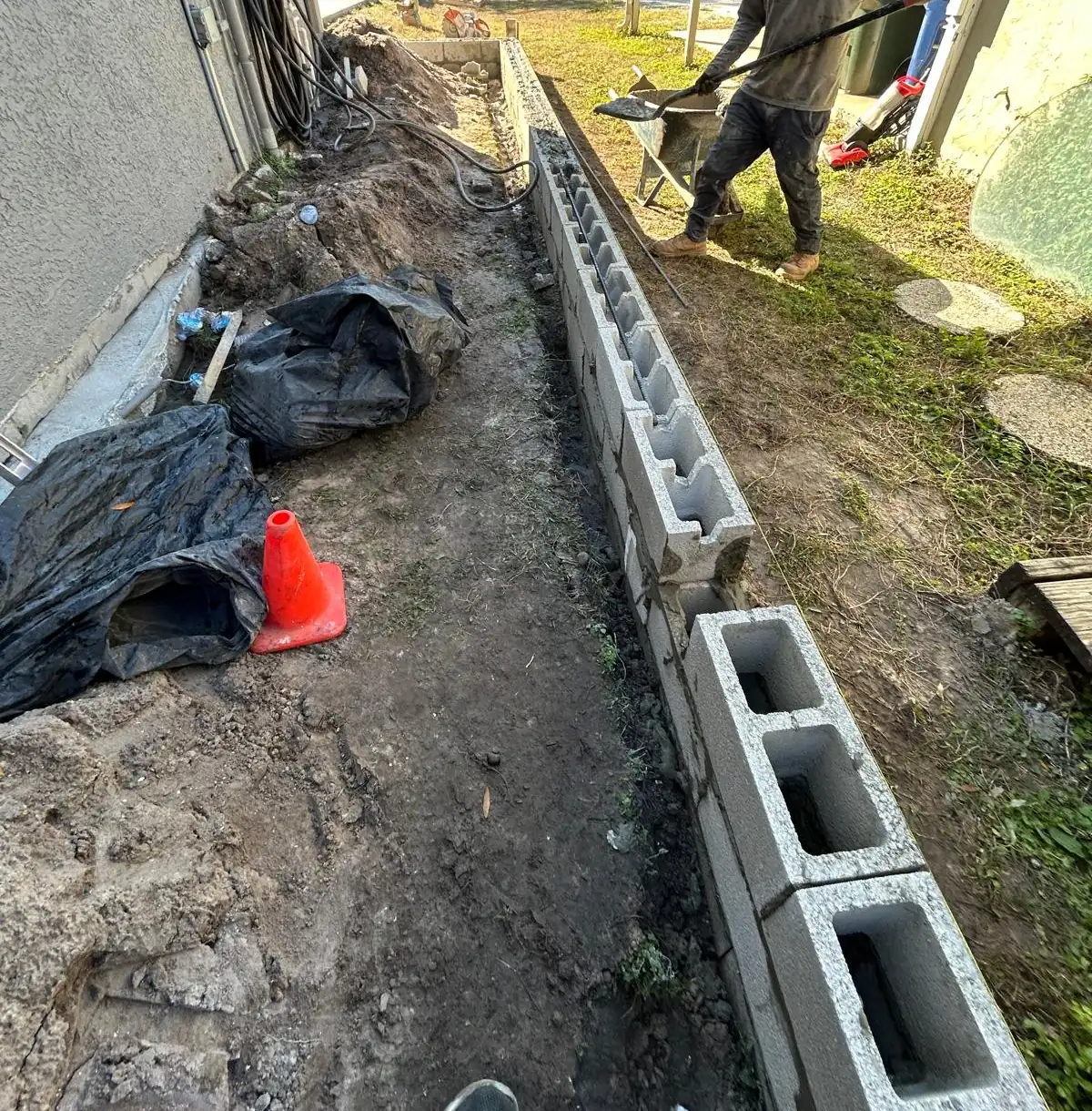 Concrete block course running the full length of the trench along the side of the house, block staged at the end