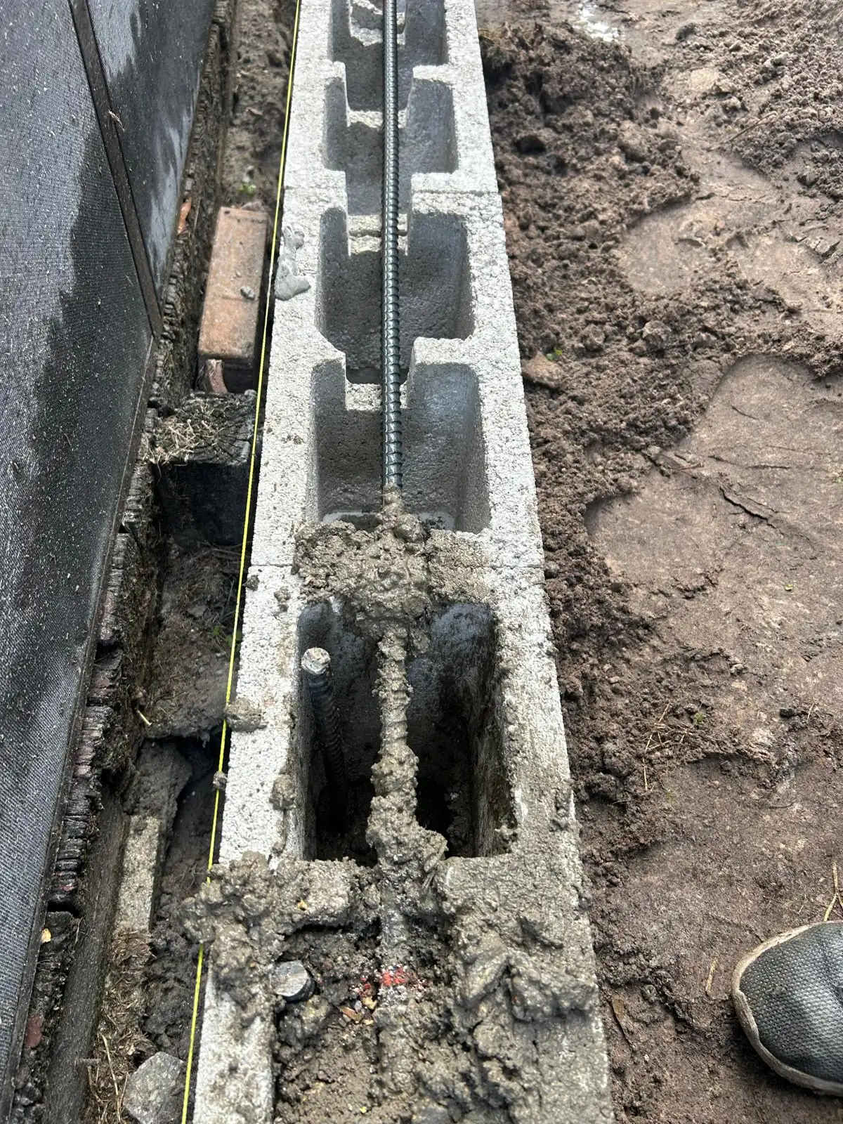 Block cell packed with mortar around the rebar, with a bar running along the cells and a string line on the face