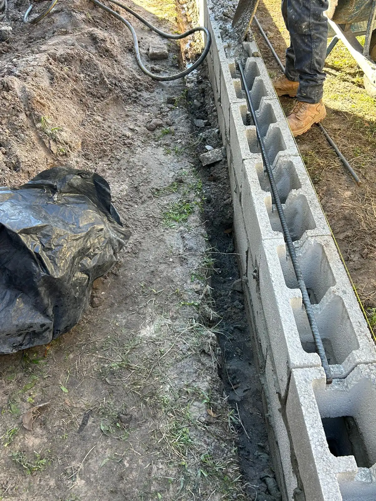Concrete block course with a length of rebar laid in the open cells along the top of the run